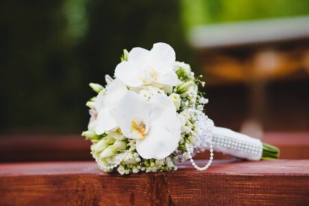 White wedding bouquet of flowers on a green background. Flowers lie on a wooden surfaceの写真素材