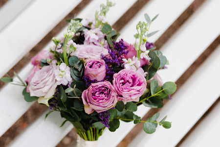 A lilac  wedding bouquet of flowers rests on a white benchの写真素材
