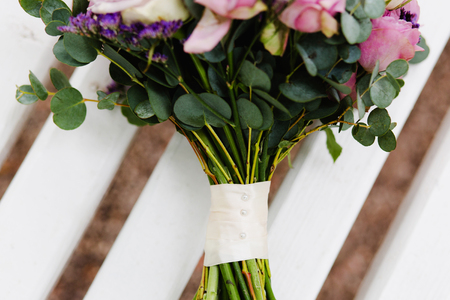 A violet wedding bouquet of flowers rests on a white benchの写真素材