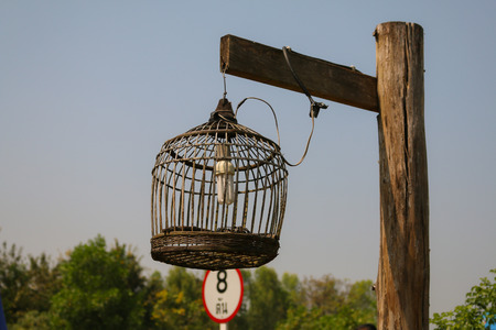 bird cage lamp on wooden postの写真素材