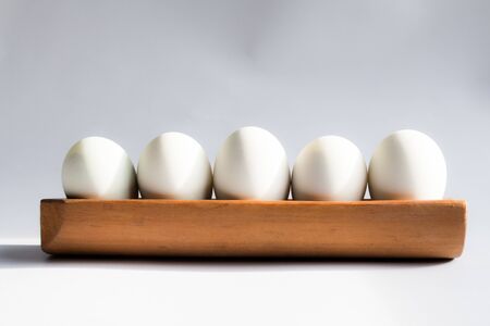 Egg in a wooden tray white backgroundの写真素材