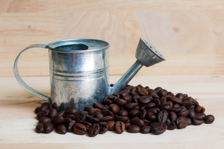 Watering Can miniature and Coffee beans wood background.の写真素材