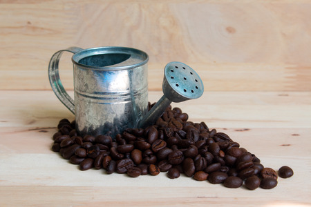 Watering Can miniature and Coffee beans wood background.の写真素材