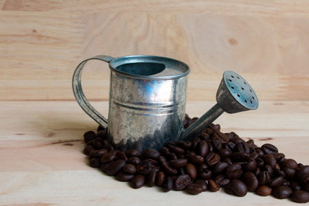 Watering Can miniature and Coffee beans wood background.の写真素材