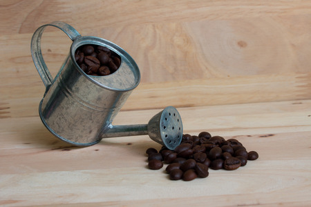 Watering Can miniature and Coffee beans wood background.の写真素材