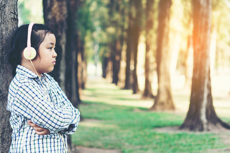 free happy cute girl enjoying. A beautiful kids hipster girl listening to music on headphones in the park.の写真素材
