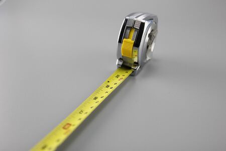 Measuring tape of 5 meters in length, placed on a gray background.