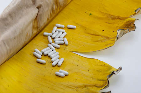 White capsules placed on banana leaves