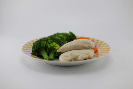 Clean food consists of boiled chicken, boiled carrots and boiled broccoli. In a bowl placed on a white backgroundの写真素材
