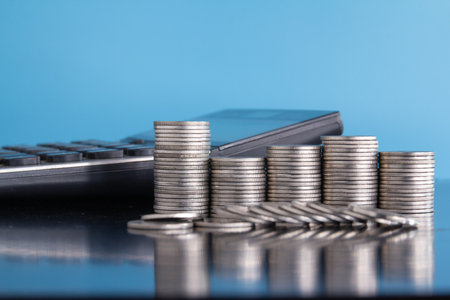 Stack of coins and calculator on blue background, Business and finance concept.の写真素材