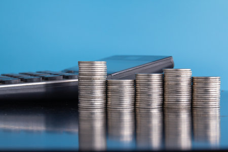 Stacks of coins and calculator on blue background. Business and finance concept.の写真素材