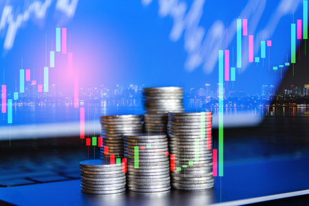 Stacks of coins with stock market chart background, business and finance conceptの写真素材