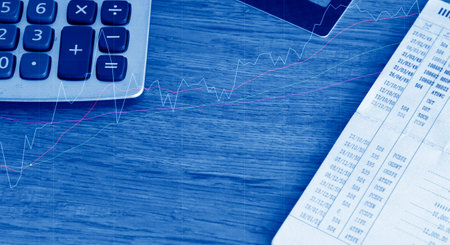 calculator on the wooden table with financial graph in blue toneの写真素材