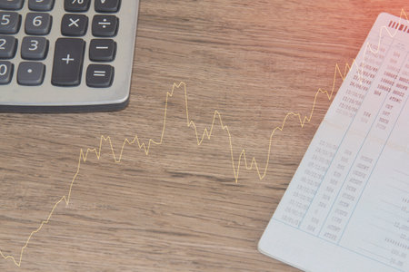 calculator and financial graph on wooden table, stock market conceptの写真素材