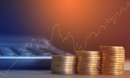 Coins stacked on each other and financial graph on the background.の写真素材