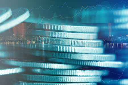 Double exposure of coin stack with financial graph and cityscape background.の写真素材