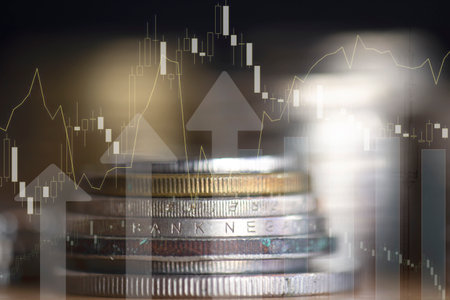 Double exposure of coin stack with stock market graph and financial chart.の写真素材