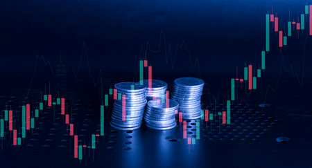 Stacks of coins and candlestick chart on a dark backgroundの写真素材