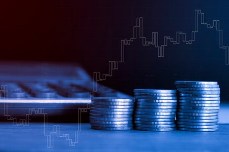 Double exposure of coin stack with financial graph and calculator on dark background.の写真素材