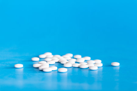 White pills on a blue background. Focus on foreground, soft bokeh.の写真素材
