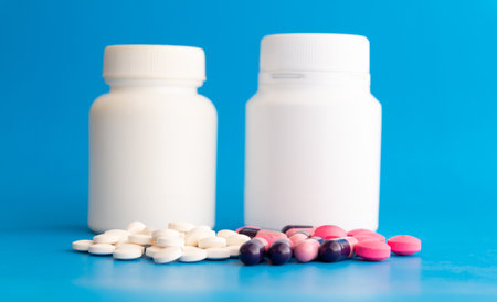 Pills and bottle on blue background. Focus on foreground, shallow DOF.の写真素材