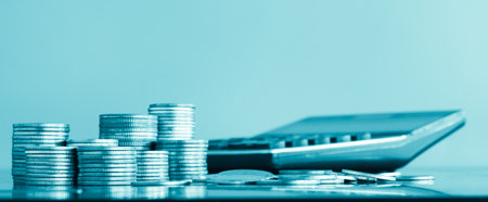 Stack of coins with calculator on blue background, business and finance concept idea.の写真素材