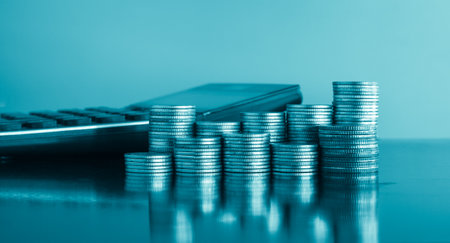 Coins stacked on each other with calculator in the background, business and finance concept idea.の写真素材