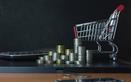 Shopping cart with coins on blackboard background, business concept.の写真素材