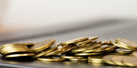 Close up of gold coins on laptop keyboard with shallow depth of fieldの写真素材