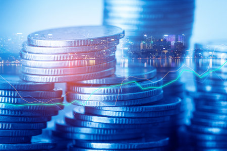Double exposure of coin stack with financial graph and cityscape background.の写真素材