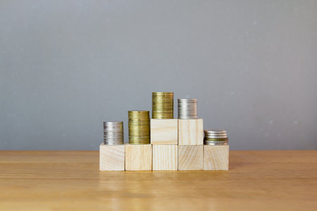 Stack of coins on wooden cubes with grey background, business and finance conceptの写真素材