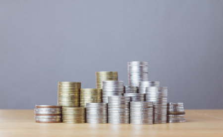 Stacks of coins on wooden table and grey background, business and finance conceptの写真素材