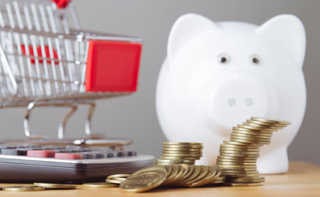 Piggy bank with coins, calculator and shopping cart on grey background.の写真素材