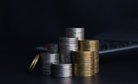Stack of coins with laptop on black background, business and finance conceptの写真素材
