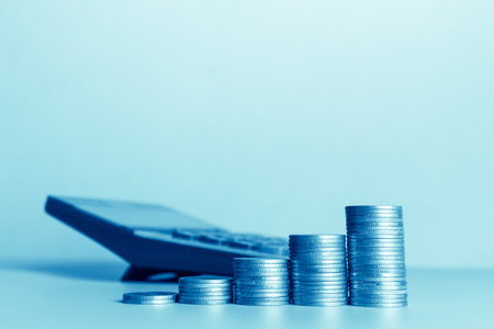 Stacks of coins and calculator on blue background, business and finance concept idea.の写真素材