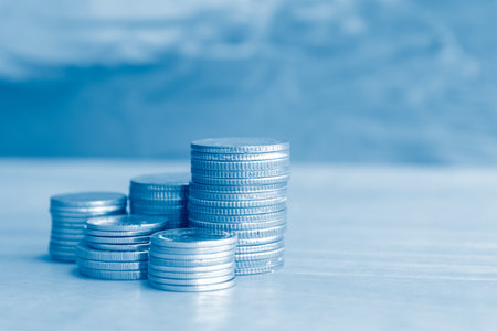 Coins stacked on each other in different positions, with blue backgroundの写真素材