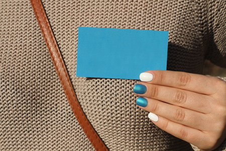 Beautiful female hand with manicure holds a blank blue card. Pearl bright blue and white nail polishの写真素材