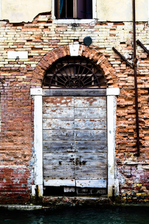 Dilapidated door opening onto a canal, Veniceの写真素材