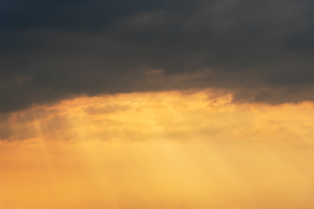 Sunlight shine through the dark cloud like a miracle backgroundの写真素材