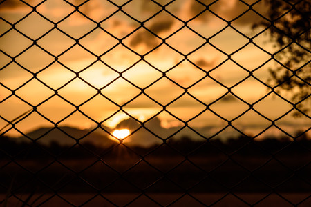 sunset behind chain link fenceの写真素材