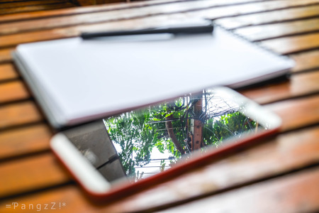 Smartphone and pen put on empty notebook on wood backgroundの写真素材