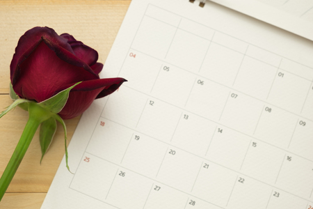 top view red roses and page of calendar put on wooden floor backgroundの写真素材