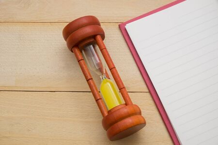 wooden sand clock and empty notebook on wooden backgroundの写真素材
