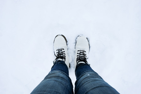 foot of woman with blue jean pants standing in snow floorの写真素材