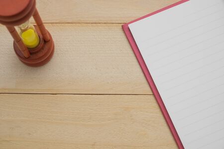 wooden sand clock and empty notebook on wooden backgroundの写真素材