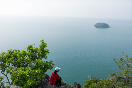 young woman sitting on cliff edge and she looking to sea with feeling sadnessの写真素材