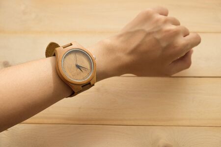 top view. business young woman equip wooden wrist watch on her arm have wooden are background. this image for equipment,accessory and fashion conceptの写真素材
