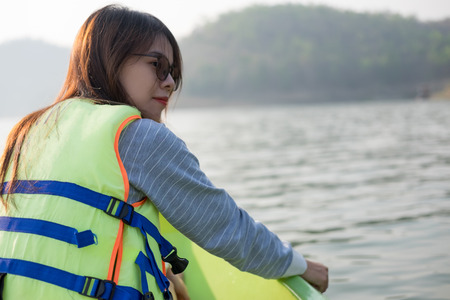 young woman equip life jacket sitting relaxing on prow. she looking side around herself have sea and...