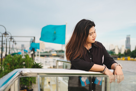 young asia woman stand alone on riverside and she looking scenery view from front her. this image for person,portrait,nature,city,travel,building conceptの写真素材