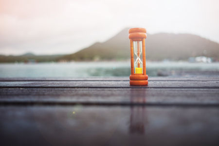 wooden sand clock placed on wooden bridge has sea, mountain, sky are background. this image for scenery, travel, nature, object, island, environment conceptの写真素材
